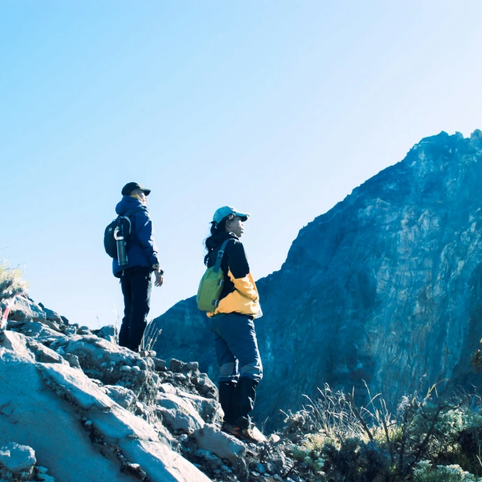 Two people are hiking on a mountain peak.